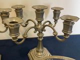 a silver candelab and a glass bowl on a table