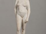 statue of a woman standing on a wooden table with a gray background