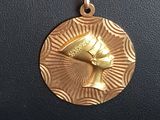 a close up of a gold necklace with a bird on it