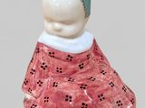 a figurine of a woman wearing a pink dress and a blue headband