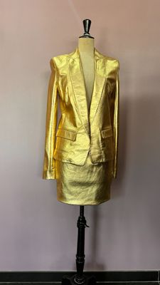 un tailleur-pantalon et un blazer dorés sur un mannequin, un mannequin, un mannequin, un mannequin, un mannequin, un mannequin, un mannequin, un mannequin