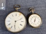 two old pocket watches sitting next to each other on a table