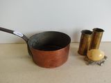 une petite casserole en métal et une petite tasse en métal posées sur une table