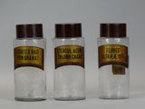 three glass jars with labels on them sitting on a table