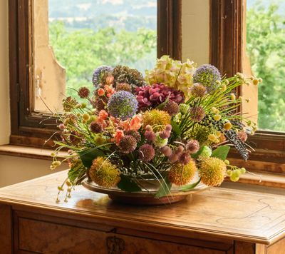 un vase de fleurs posé sur une table devant une fenêtre