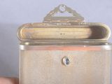 a small silver box with a metal handle in someone ' s hand