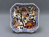 un petit plat carré orné de fleurs et d'oiseaux