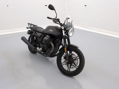 une moto noire garée dans une pièce aux murs blancs