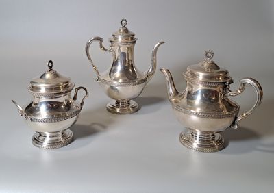 trois théières en argent et une théière en argent posées sur une table