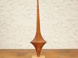 a wooden sculpture on a table with a white wall in the background
