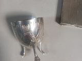 a silver cup sitting on a table next to a mirror