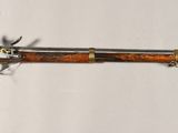 un fusil en bois accroché au mur, à côté d'un mur blanc