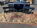 plusieurs chaises et une table dans une pièce dont le sol est recouvert d'un tapis