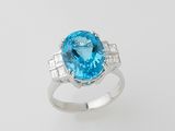 a close up of a ring with a blue topaz stone and diamonds