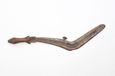 an old knife with a wooden handle sitting on top of a white surface