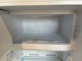 a small white refrigerator with a bed inside of it