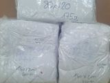 three bags of white blankets are stacked on top of a cardboard box