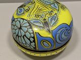 boîte décorative jaune et bleue posée sur une surface blanche