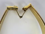 an image of a pair of gold toned bracelets on a white surface