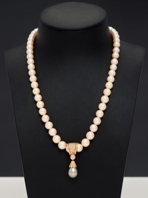 un collier en perles et en or avec un pendentif, porté par un mannequin