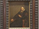 portrait d'un homme barbu assis sur une chaise près d'un mur