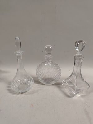 trois flacons de parfum en verre transparent posés sur une table blanche