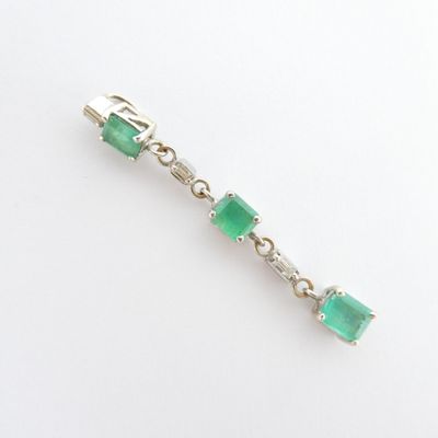 un gros plan sur un bracelet en émeraude verte et diamants