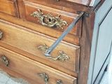 a wooden chest of drawers with a metal handle on it