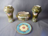 three vases and a plate sitting on a table