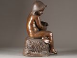bronze statue of a woman sitting on a rock holding a baby