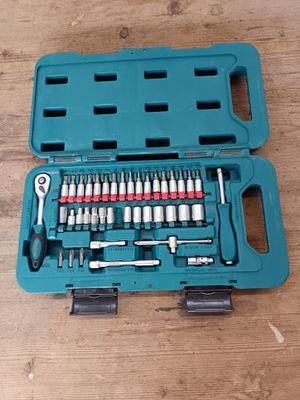 un ensemble d'outils rangé dans une mallette bleue, posé sur une table en bois