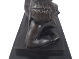 statue of a woman with a basket on her head on a black base