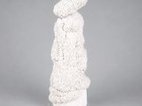 une sculpture blanche représentant une femme debout sur un socle blanc