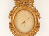 a gold clock on the wall with a bird on it