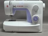 La machine à coudre est posée sur la table, prête à l'emploi.