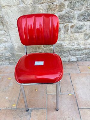 une chaise rouge posée devant un mur de pierre