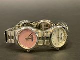 a silver watch with a pink face on a table