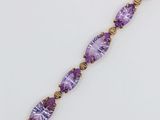 a close up of a bracelet with purple stones on a white surface