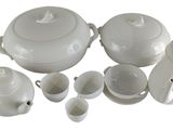 a white tea set with cups and saucers on a white table