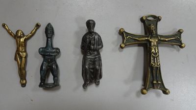 three metal figurines of a man and a cross