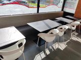 tables and chairs in a restaurant with a view of a parking lot