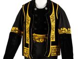 une veste noire et dorée, ornée de passementeries dorées, posée sur une tête de mannequin