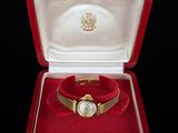 an image of a gold watch in a red box on a black surface