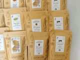 six bags of coffee sit on top of each other in front of a white wall