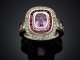 a close up of a pink sapphire and diamond ring on a black surface