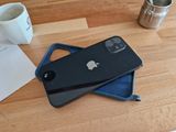 a black iphone sitting on top of a wooden table next to a cup of coffee