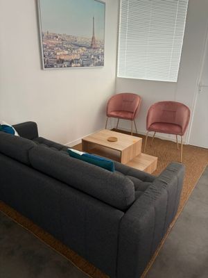 un salon avec un canapé, un fauteuil, une table basse et une télévision
