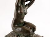 l'image d'une statue de bronze représentant une femme assise sur un rocher