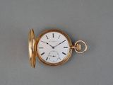 une montre de poche en or posée sur une surface grise
