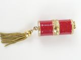 a close up of a red and gold necklace with a tassel